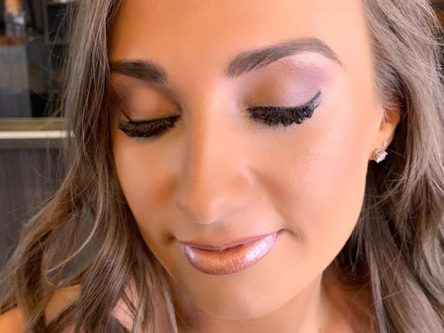 Close up view of women's makeup with eyelashes, natural pink eyeshadow and metallic lips